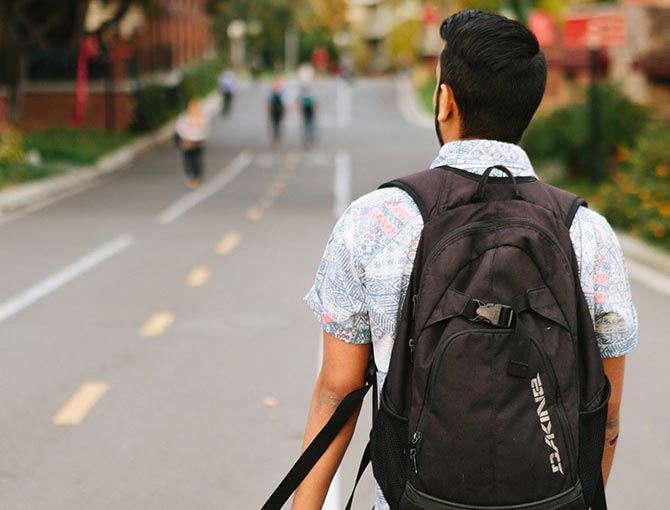 A student wearing a backpack walks down the path by the cafeteria