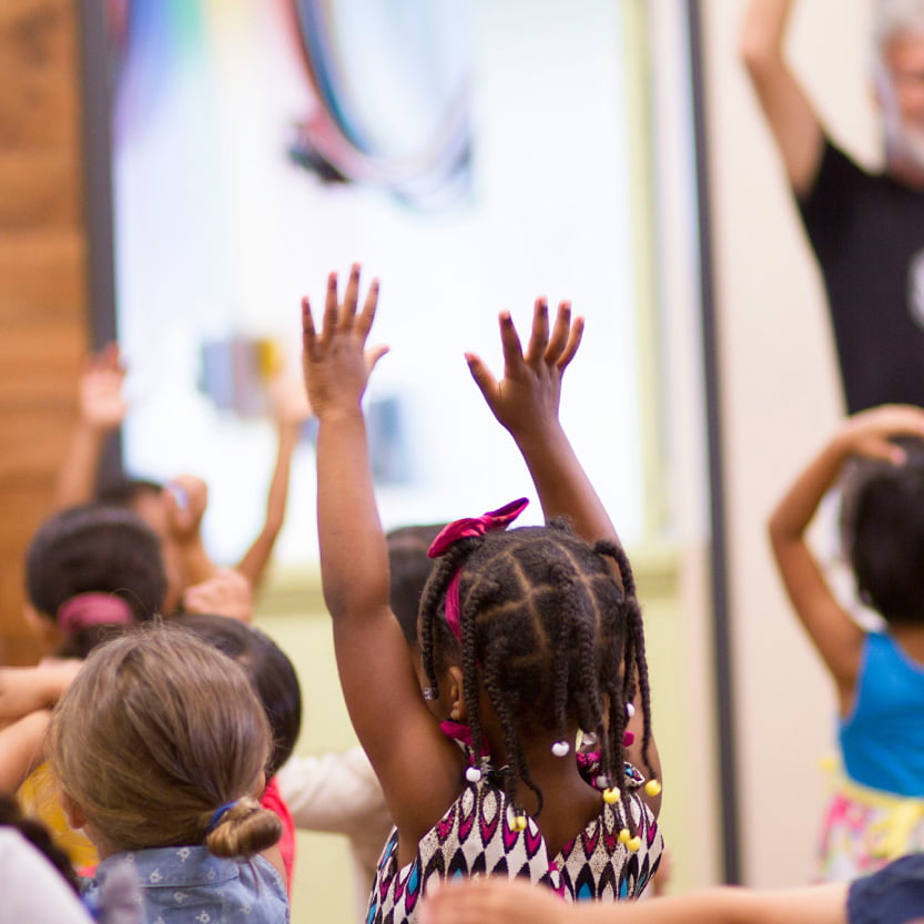 kids singing and raising hands