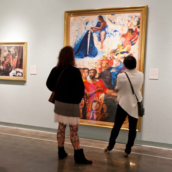 two women observing a painting in a gallery