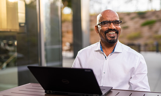 A student smiles while sitting with a laptop