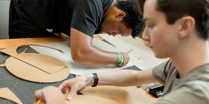 Students cutting out geometrical designs on a work table