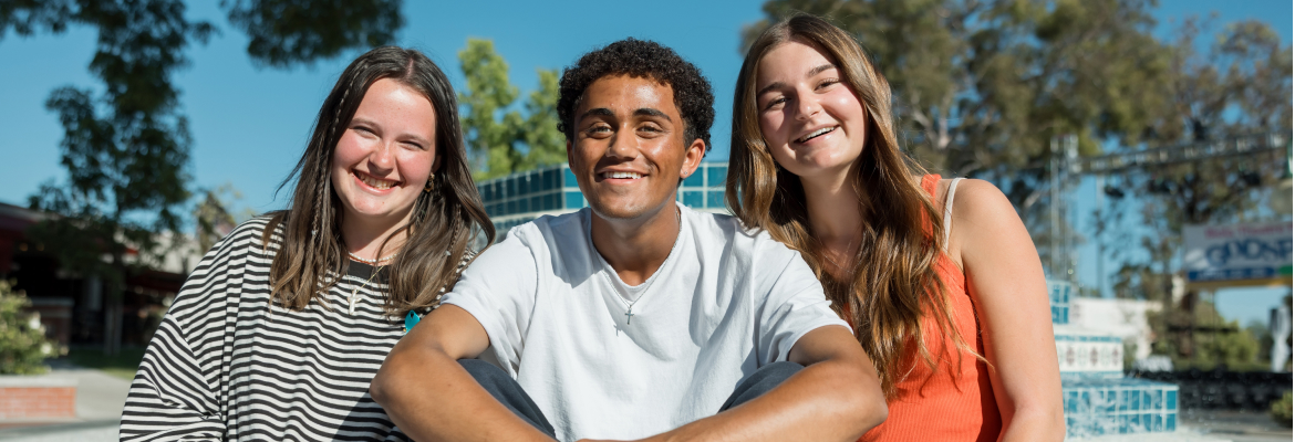 Group of students smiling together in front of a fountain. 