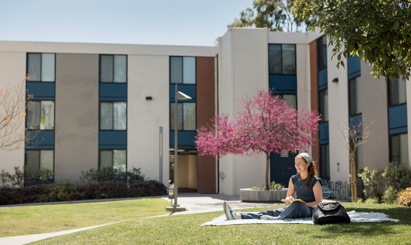 Female student studying on the lawn by Sigma Hall