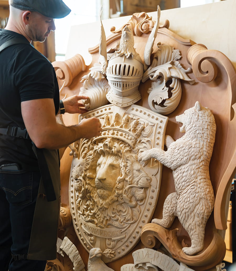 Jake Weidmann working on a large wooden family crest