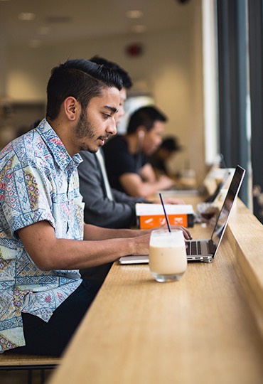 A student types on a laptop at a coffee shop.