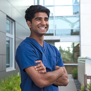 A student in medical scrubs poses for the camera.
