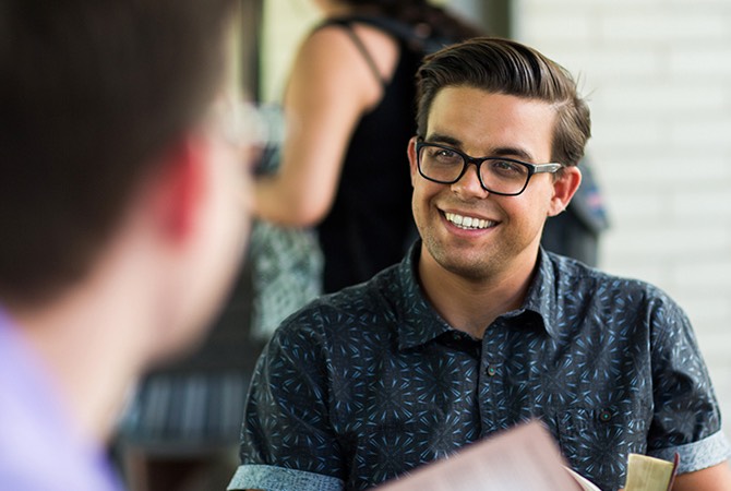 A student smiles while discussing the Bible with a friend.
