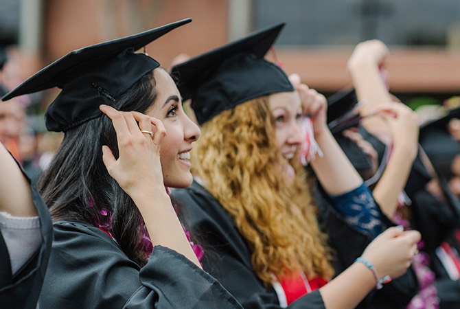 Students smile in their graduation caps and gowns.