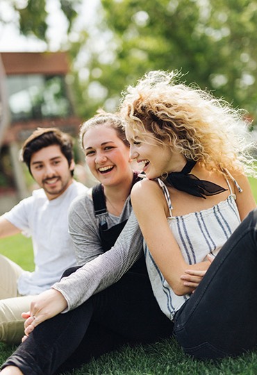 A group of students laugh together on Metzger Lawn.