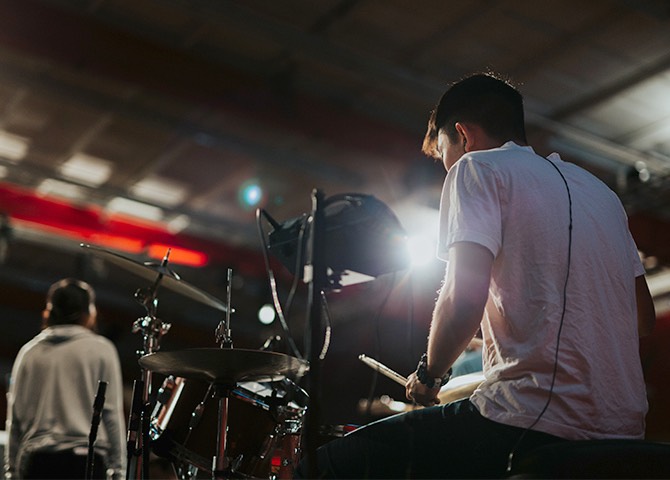 Reverse shot of a drummer, performing on a stage.
