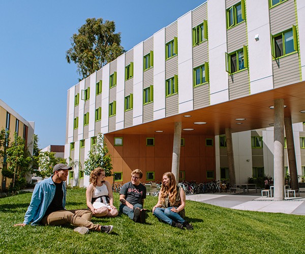 Four students talk on the lawn in front of Blackstone Hall.