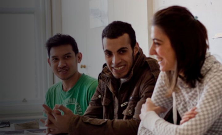 Students at a desk smile and talk to each other