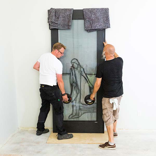 Two men moving a panel of stained glass