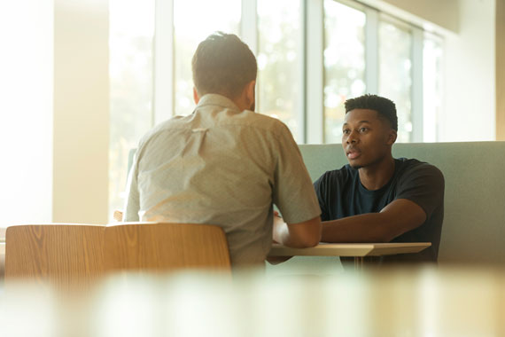 Two men in conversation sitting at a table