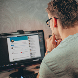 Man looking at a social media profile on a computer screen.
