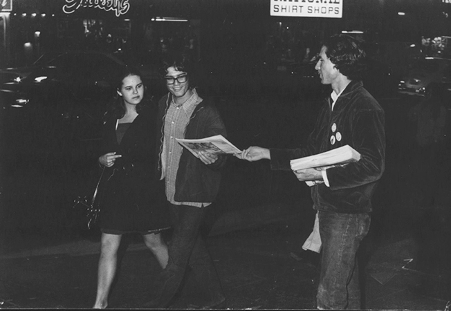 Man passing out flyer to two women