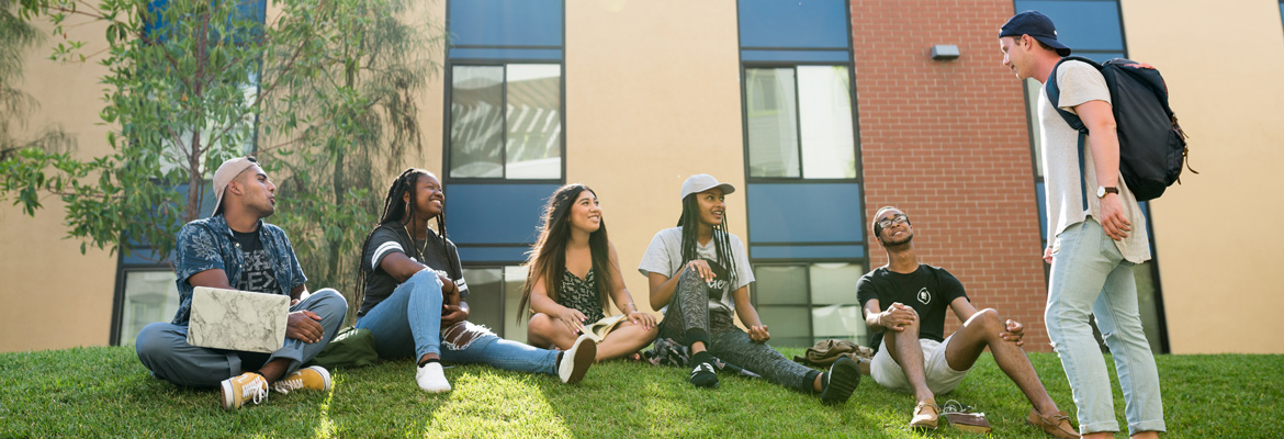 Students in sitting on grass in front of residence hall