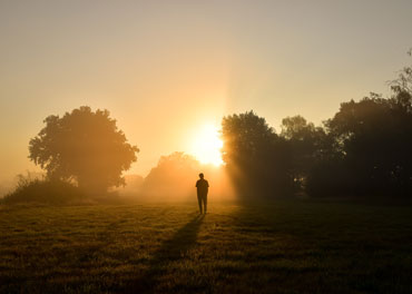 Man walking into a sunrise