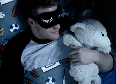 Male sleeping with stuffed animal lamb