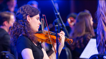 A female student playing the violin during a concert.