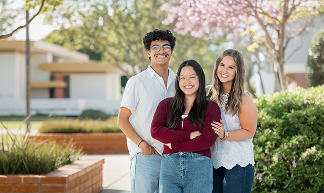 three students smiling on Biola's campus