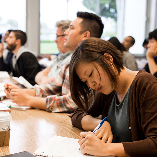 Woman writing in her notebook in a classroom.