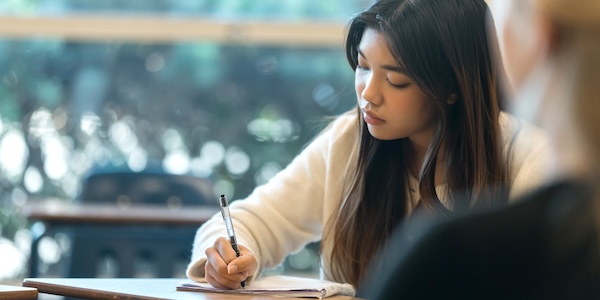 A female student writing at her desk.