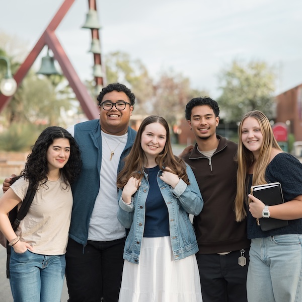 A group of students smile for a picture in front of the Biola Bell Tower