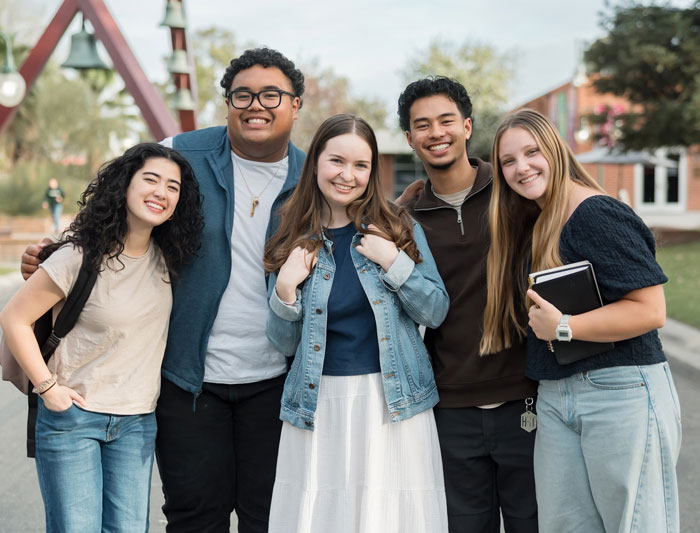 A group of students smiling in front of the Bell Tower