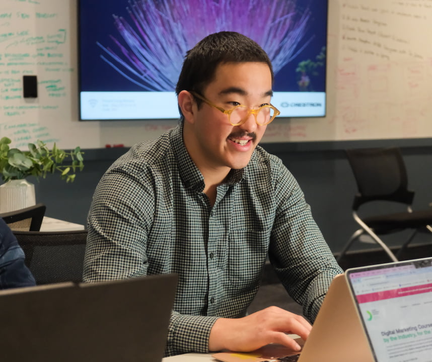 Male student sitting at table with laptop.