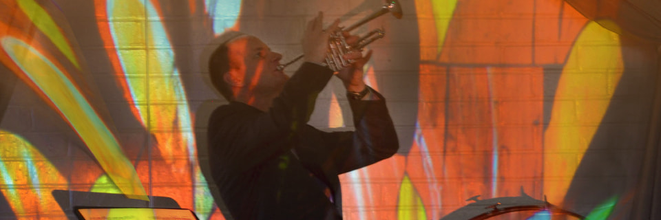 abstract image projected on a wall with man playing trumpet