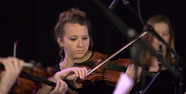 A female violinist playing during a concert.