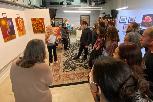 woman talking to a crowd at an art gallery