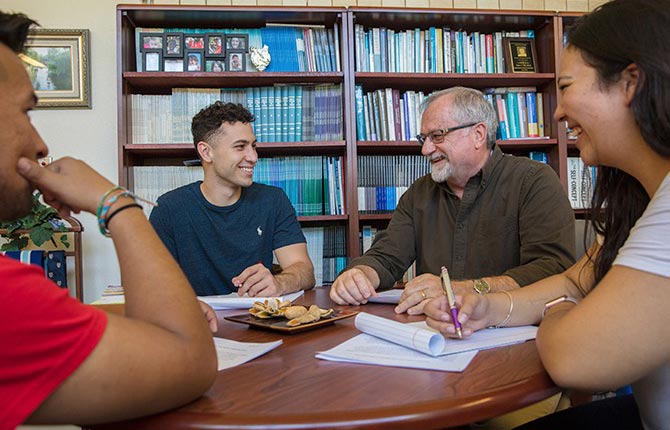 A group of students meets with a professor in his office