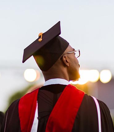 A student in a cap and gown sits during graduation ceremony