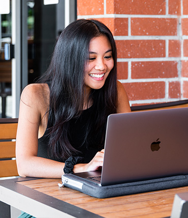 A student smiles while working on a laptop