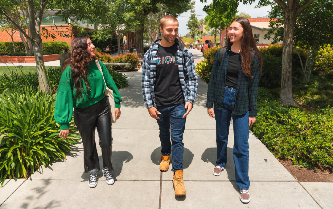 Biola students walk together on sidewalk next to the library.