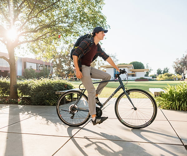 Student riding bike on walkway