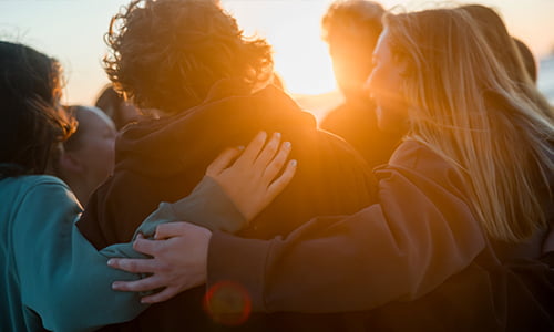 Students in a group with arms around each other