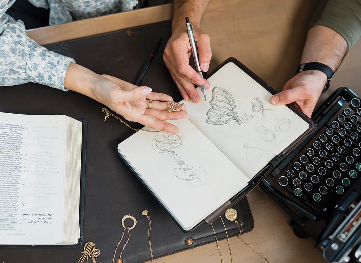 a sketchbook surrounded by several pieces of jewelry