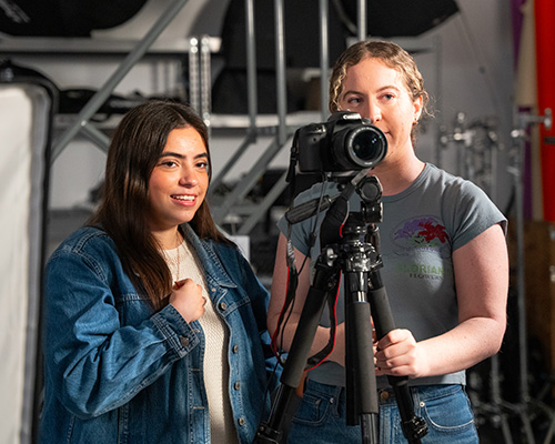 Students standing behind a camera on a film set