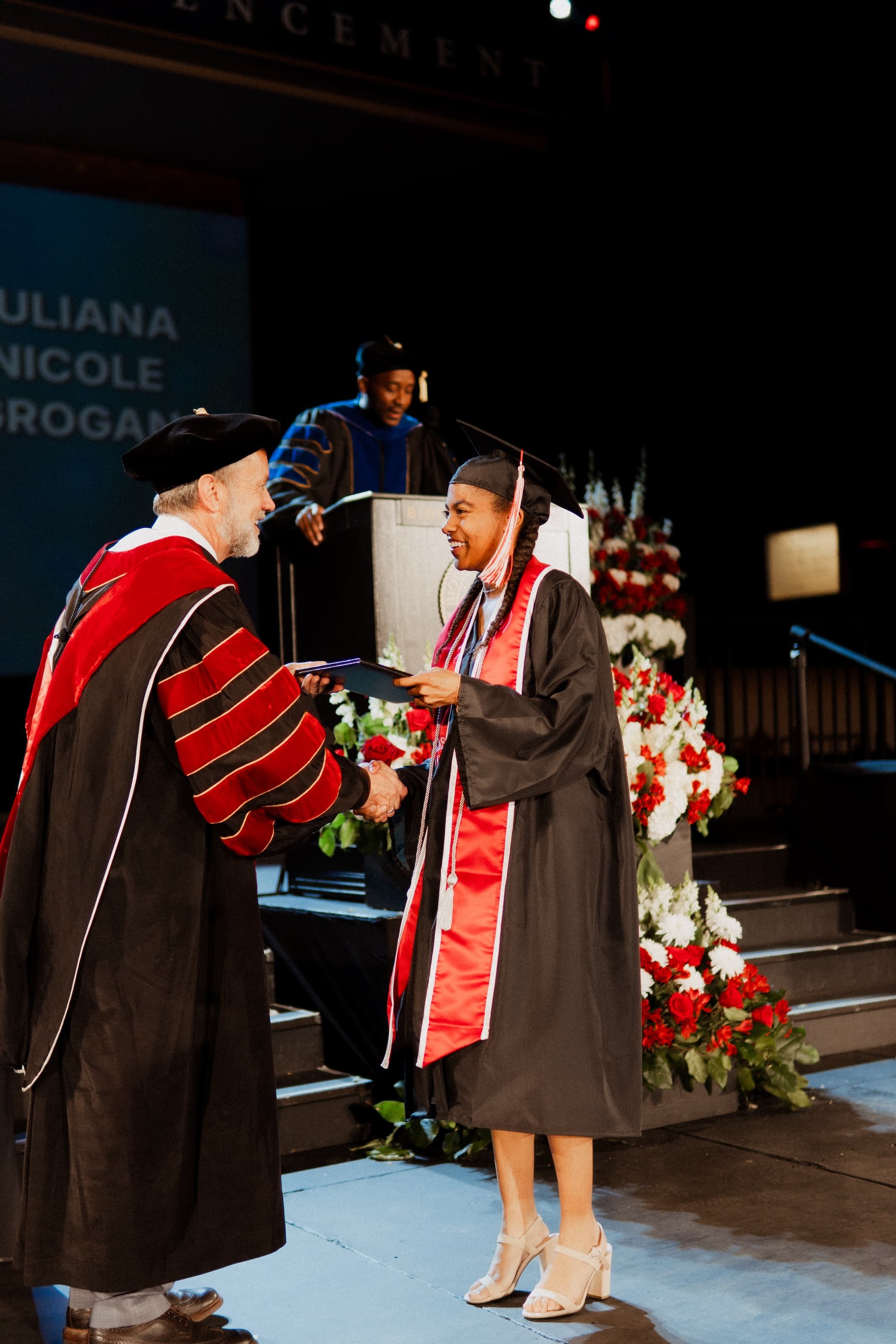 Image shows a graduate receiving her diploma