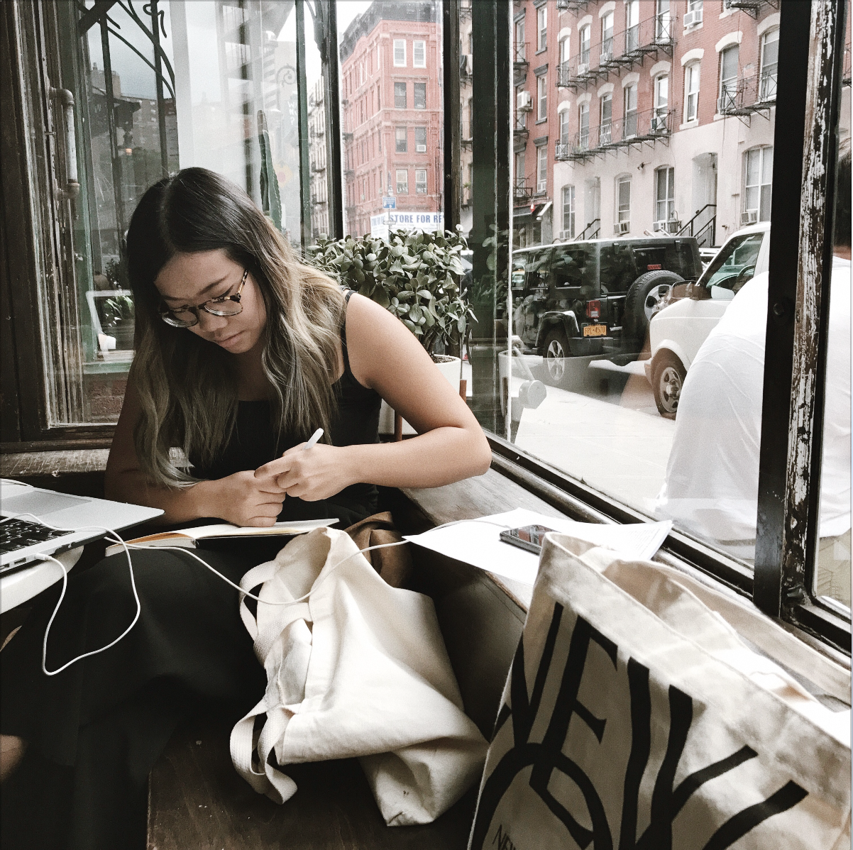 Leah Lu writing at a coffee shop in New York