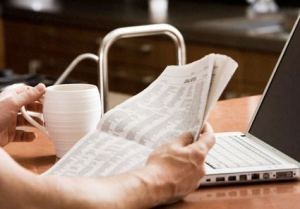 Person reading the newspaper and drinking coffee