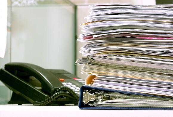 Large stack of papers and office telephone