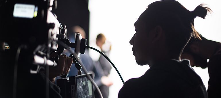 Silhouette of the profile of a male Asian student with a camera.