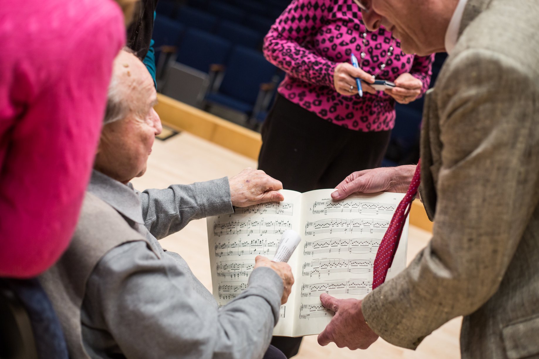 Pressler looking at sheet music with faculty members and students.