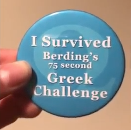 Person holding button that reads: "I SURVIVED BERDING'S 75 SECOND GREEK CHALLENGE"