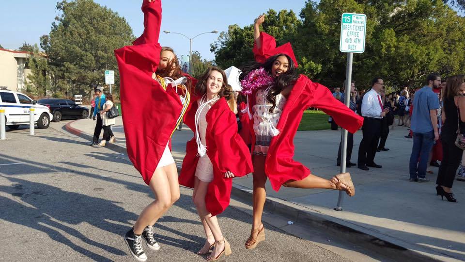 Aubrey and friends jumping at graduation in cap and gown