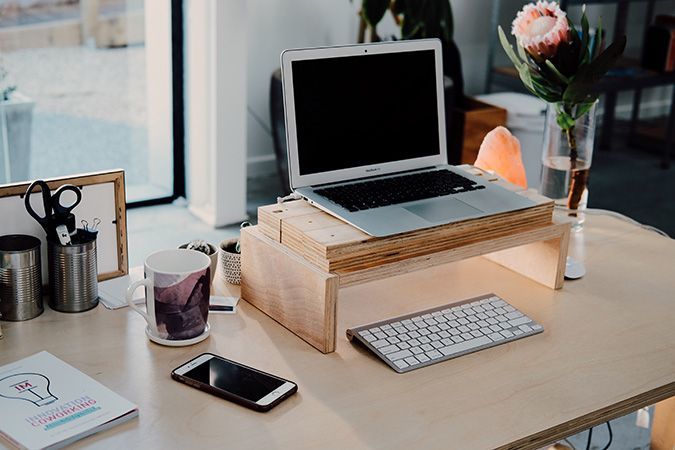 A desk with a laptop elevated on a wooden stand